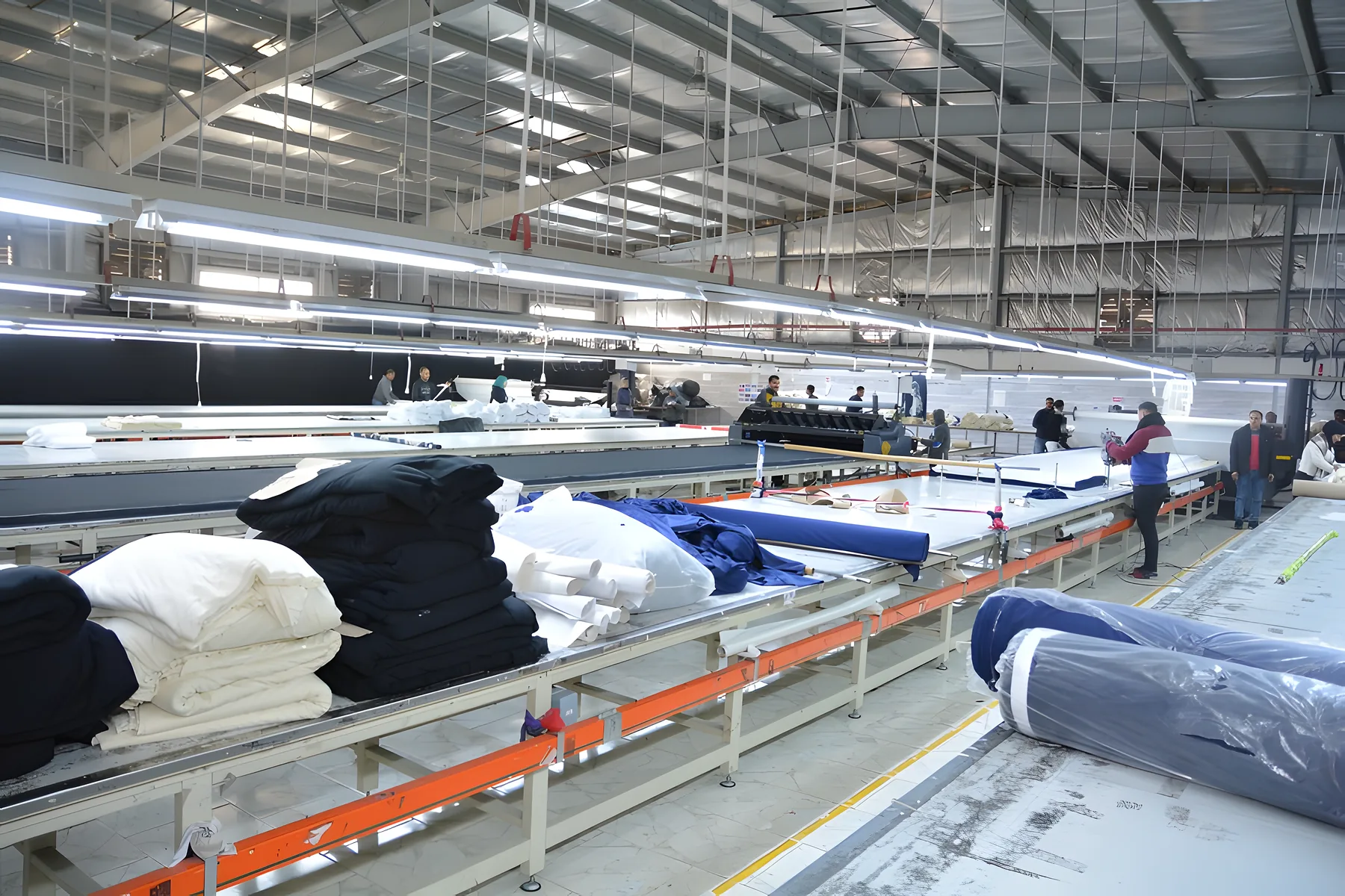 Rolls of black, navy and white knit fabric on a cutting-room table