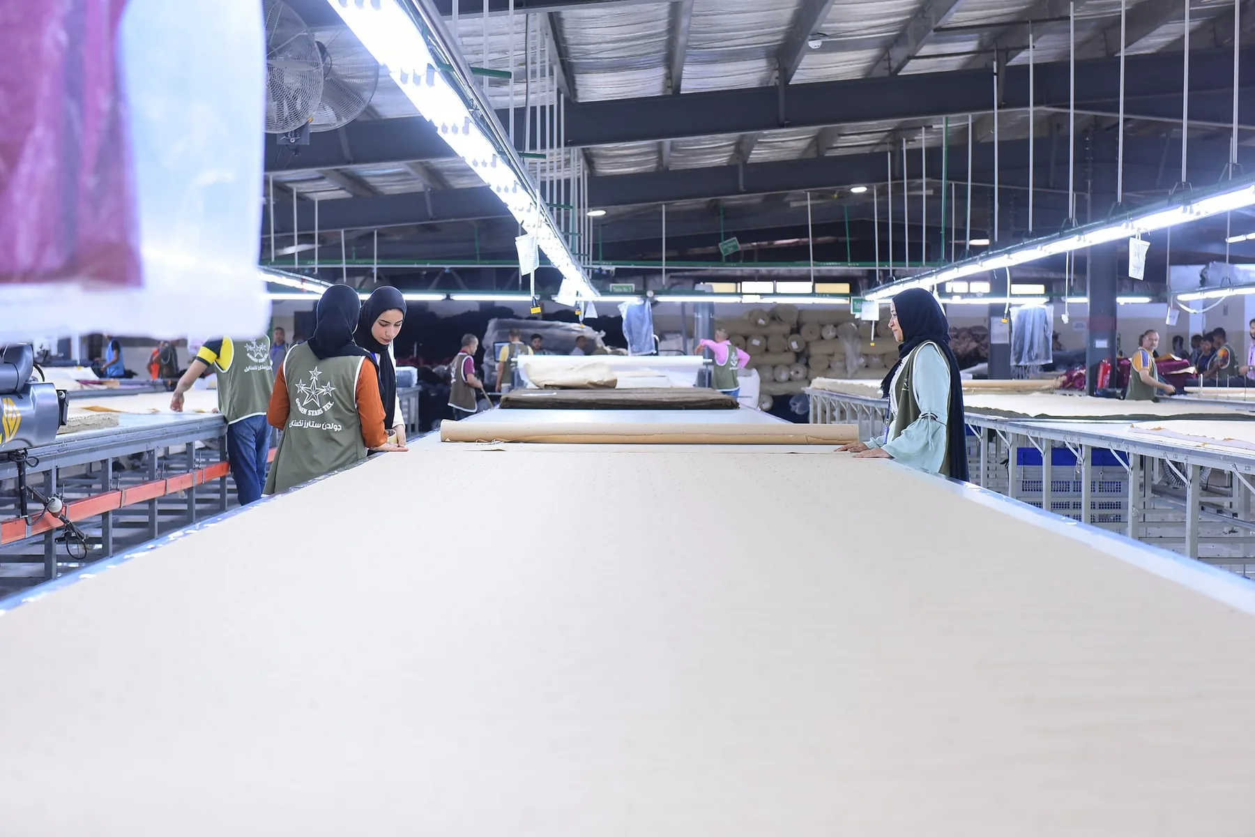 Operators spreading fabric along the cutting tables